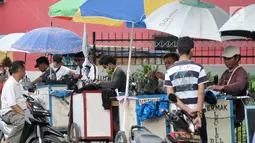 Sejumlah penjahit keliling saat menerima orderan pelanggan, Jakarta, Kamis (22/6). Para penjahit yang biasanya berkeliling masuk kampung ini lebih memilih untuk mangkal di saat jelang lebaran. (Liputan6.com/Yoppy Renato)