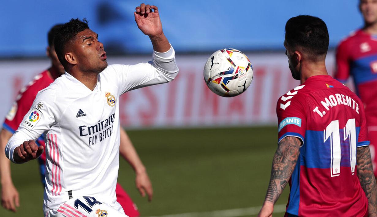 Gelandang Real Madrid, Casemiro, berebut bola dengan pemain Elche, Tete Morente, pada laga Liga Spanyol di Stadion Alfredo di Stefano, Sabtu (13/3/2021). Real Madrid menang dengan skor 2-1. (AP/Bernat Armangue)