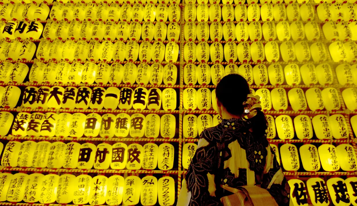 Seorang wanita berada di depan lentera saat menghadiri Festival Mitama di Kuil Yasukuni, Tokyo, Jepang, (13/7). Acara ini menghadirkan sekitar 30.000 lentera untuk mengenang korban perang.  (AFP Photo/Toru Yamanka)