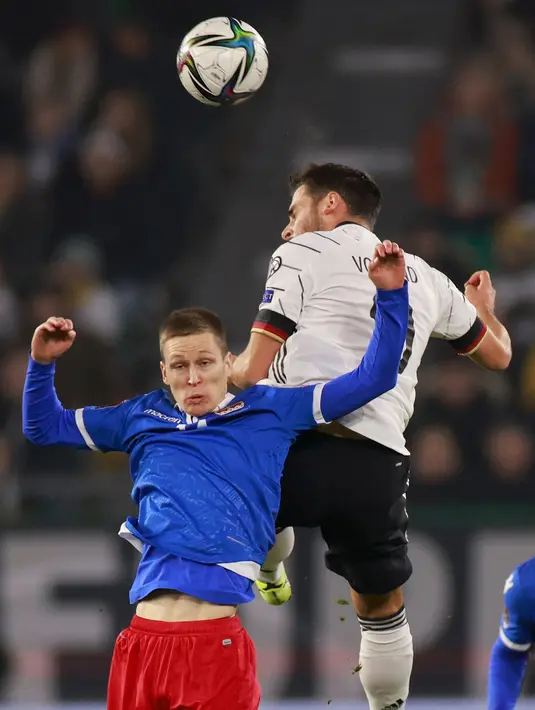 Gelandang Liechtenstein Livio Meier (kiri) berebut bola dengan pemain depan Jerman Kevin Volland pada Kualifikasi Piala Dunia 2022 Zona Eropa di Volskwagen Arena, Jumat (12/11/2021) dinihari WIB. Die National Mannschaft -julukan Jerman- menang 9-0 atas tamunya tersebut. (Odd ANDERSEN / AFP)