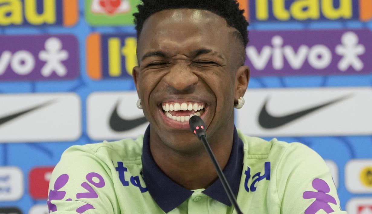 Vinicius Junior tertawa geli karena ulah si kucing yang tiba-tiba jadi penyusup di konferensi pers timnya. (AP/Andre Penner)