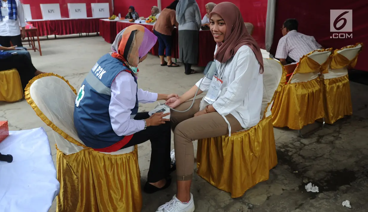 Petugas medis Puskesmas memeriksa tekanan darah petugas Kelompok Penyelenggara Pemungutan Suara (KPPS) yang bertugas saat pemungutan suara ulang di TPS 49 Rengas, Ciputat Timur, Tangsel, Rabu (24/4). Pemeriksaan untuk antisipasi menurunnya kesehatan fisik akibat kelelahan. (merdeka.com/Arie Basuki)