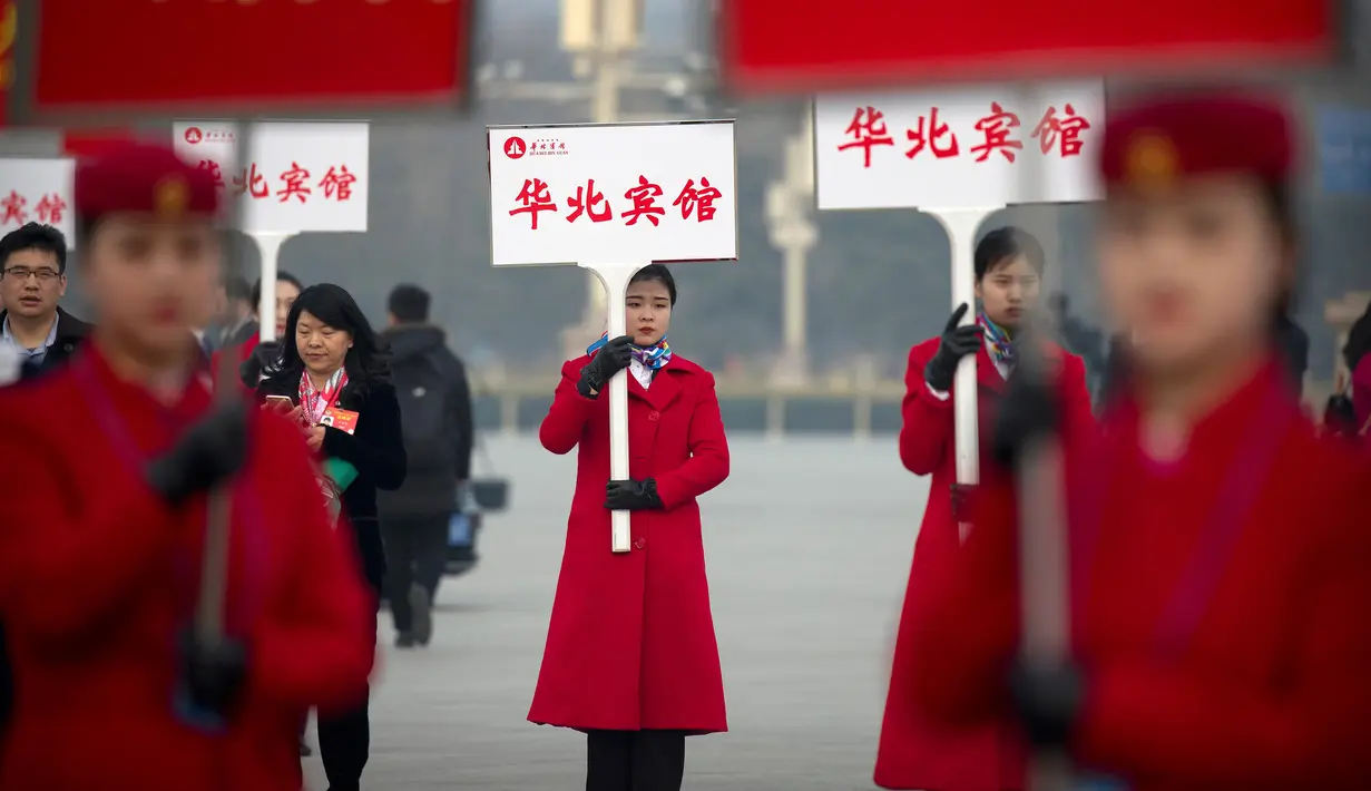 Sejumlah wanita memegang papan pengarahan saat menyambut peserta Kongres Rakyat Nasional di Beijing, China, Senin (4/3). Kongres ini dihadiri ribuan delegasi dari seluruh China. (AP Photo/Andy Wong)