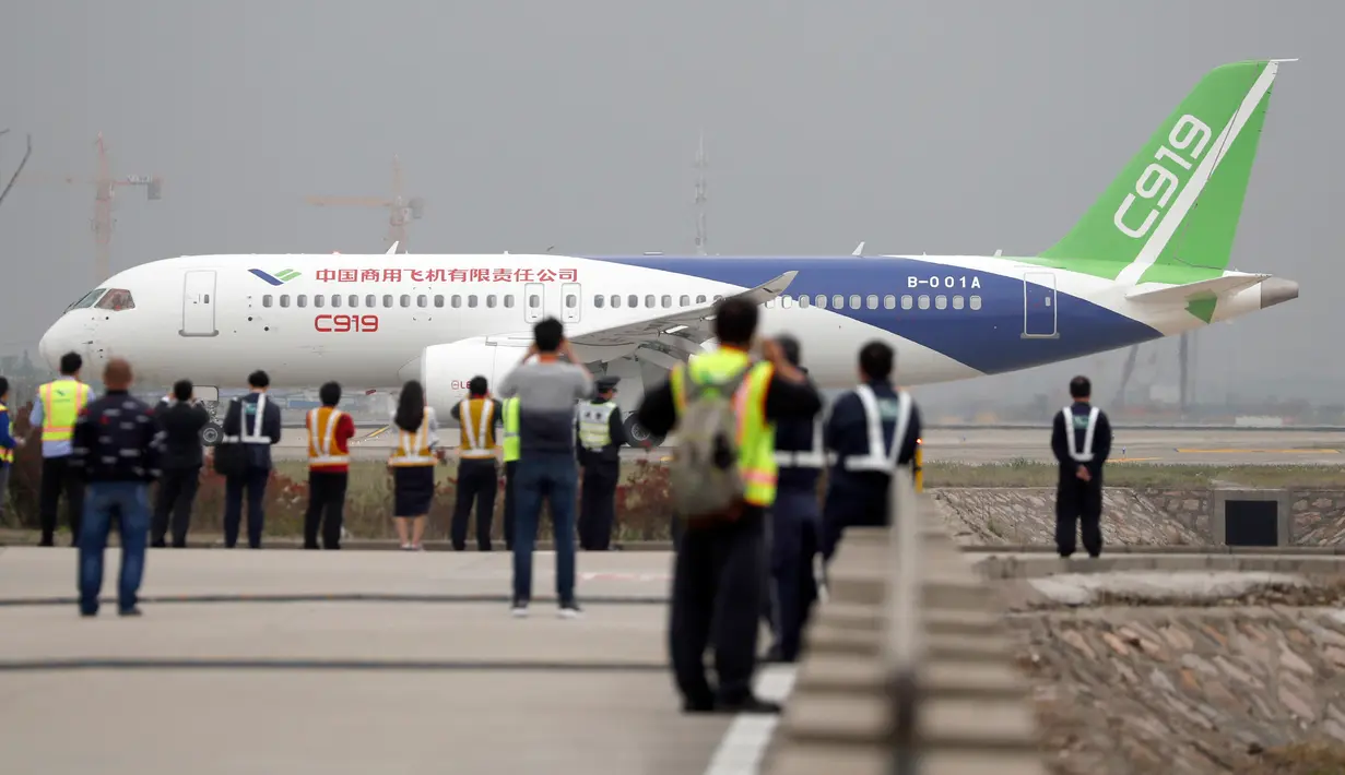 Sejumlah orang melihat penerbangan perdana pesawat penumpang jet C919 di Bandara Internasional Pudong, Shanghai, Jumat (5/5). Pesawat penumpang pertama buatan China itu akan menjalani uji terbang di ketinggian 3.000 meter. (AP Photo/Andy Wong, Pool)