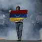 Seorang pengunjuk rasa membentangkan bendera Venezuela (AP Photo/Ariana Cubillos)