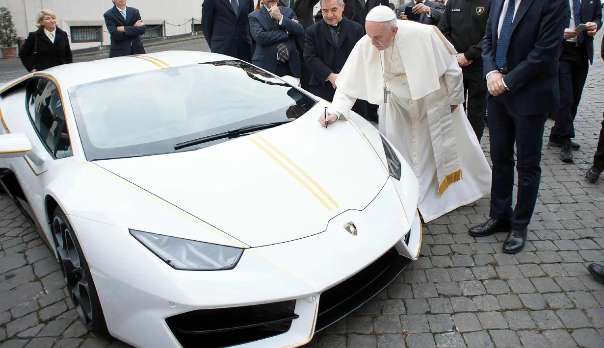 Paus Fransiskus memberikan tanda tangan di kap mesin Lamborghini Huracan di Vatikan, Rabu (15/11). Perusahaan Lamborghini memberi hadiah mobil Lamborghini Huracan berwarna putih untuk Paus Fransiskus. (L'Osservatore Romano/Pool Photo via AP)