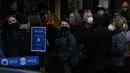 Orang-orang mengantre mengenakan masker melawan virus corona, di luar teater untuk pertunjukan Les Miserables di London, Selasa (28/12/2021). Di Inggris, pemerintah telah mengatakan bahwa tidak akan ada pembatasan baru sebelum Tahun Baru. (AP Photo/Alastair Grant)