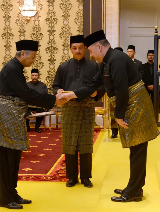 Perdana Menteri Malaysia baru, Mahathir Mohamad (kiri) bersalaman dengan Raja Malaysia Muhammad V saat prosesi sumpah jabatan di Istana Nasional di Kuala Lumpur (10/5). (AFP Photo/ Istana Nasional Malaysia)