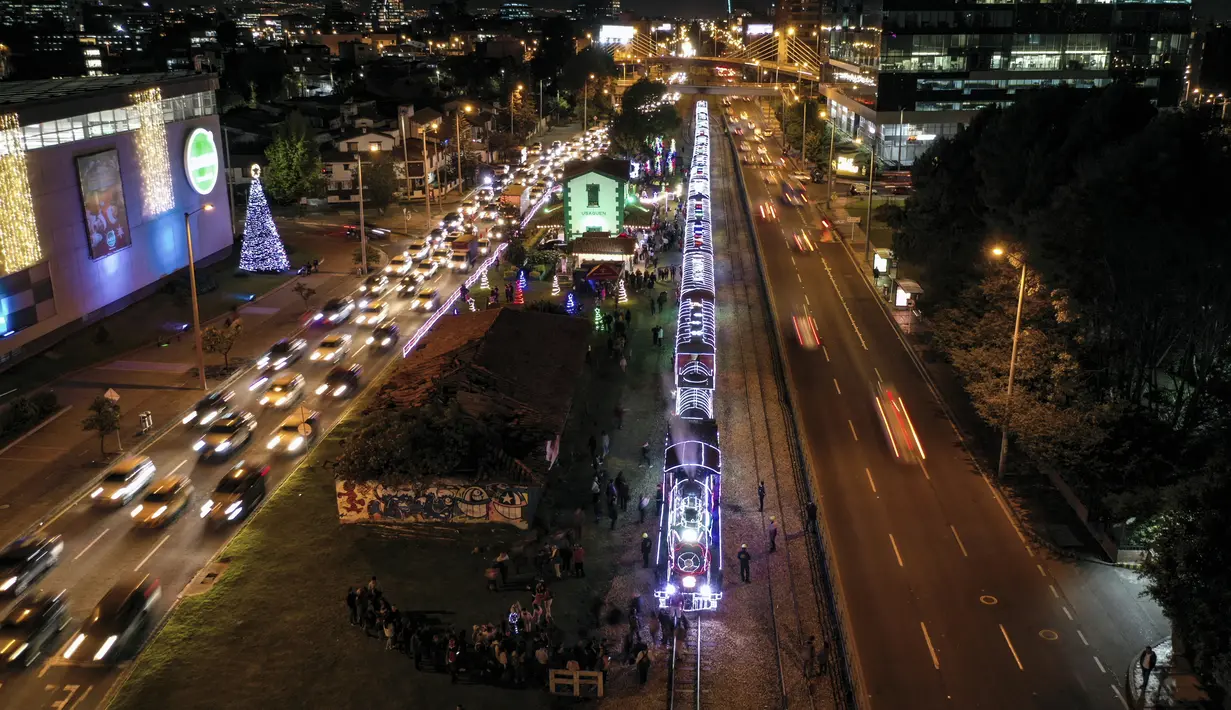 Foto udara kereta wisata yang dihiasi lampu Natal di Bogota (20/12/2019). Meyambut Hari Natal, kereta wisata di Kolombia membuat cara unik dengan memasangkan lampu warna-warni agar menjadi daya tarik penumpang. (AFP Photo/Guillermo Munoz)
