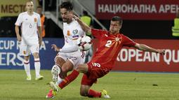 Isco (kiri) berebut bola dengan pemain Makedonia, Kristijan Tosevski pada laga kualifikasi Piala Dunia 2018 grup G di Philip II National Stadium, Skopje, MaKedonia, (11/6/2017). (AP/Boris Grdanoski)