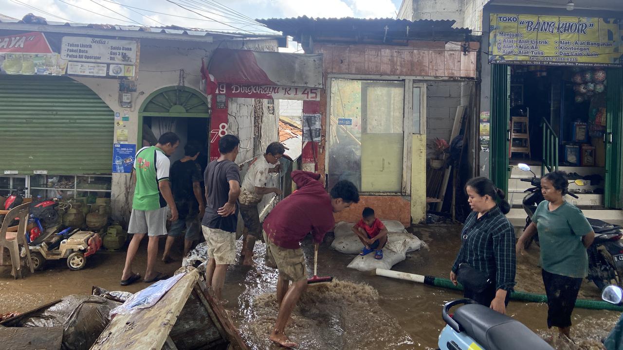 Warga terlihat bergotong royong membersihkan rumah mereka dari banjir Jakarta.