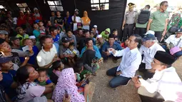 Presiden Joko Widodo atau Jokowi bersama Gubernur NTB Tuan Guru Bajang (TGB) Zainul Majdi berbincang dengan warga saat mengunjungi korban gempa di Desa Madayin, Sambelia, Lombok Timur, NTB, Senin (30/7). (Agus Suparto/Indonesian Presidential Palace/AFP)