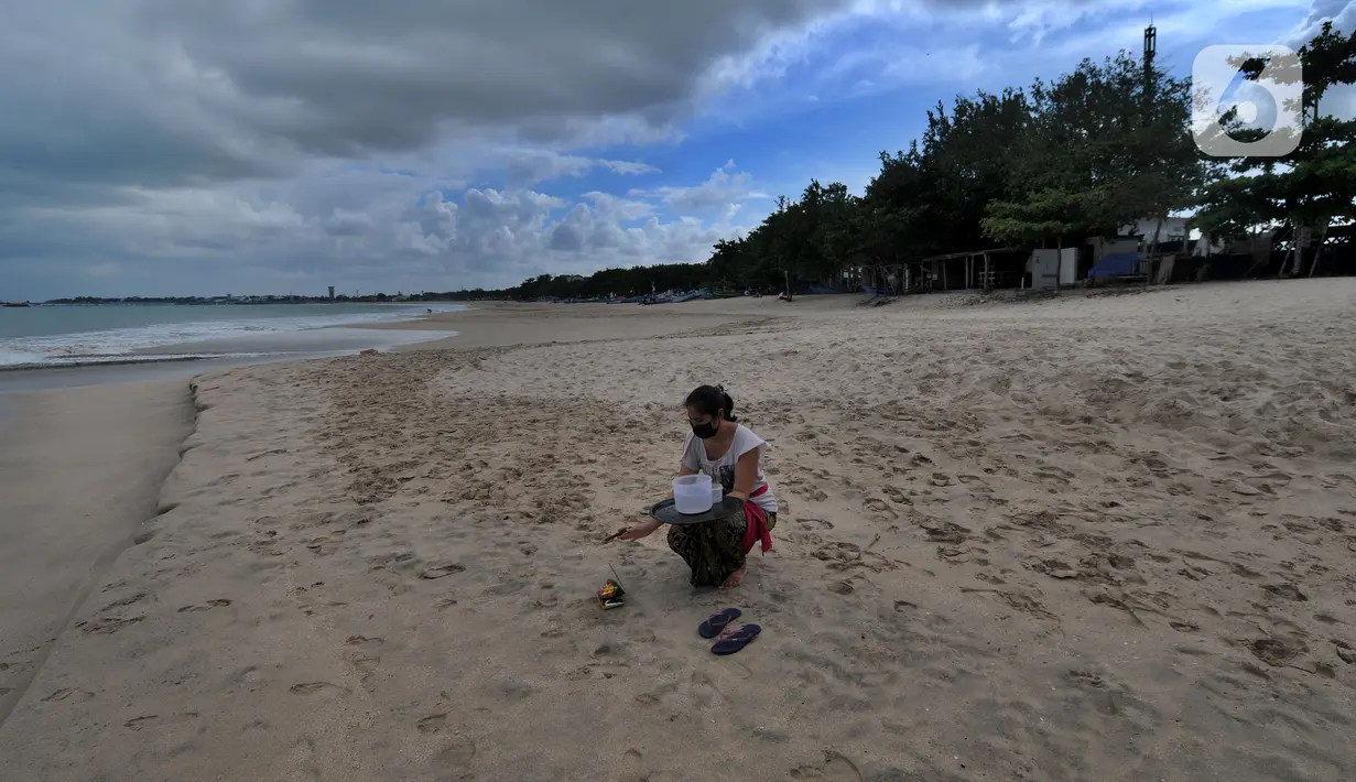Umat Hindu bersembahyang di kawasan Pantai Jimbaran, Bali, Jumat (3/9/2021). Sepinya wisatawan yang datang ke Pulau Bali selama PPKM Darurat yakni hanya sebesar rata-rata 500 wisatawan lokal menyebabkan sejumlah tempat wisata pantai sepi pengunjung. (merdeka.com/Arie Basuki)
