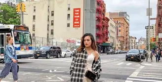 Kamu bisa juga memadukan long plaid shirt yang boyish dengan baggy pants warna krem, dan white tank top nan feminin seperti Beby Tsabina satu ini. (Instagram/bebytsabina).