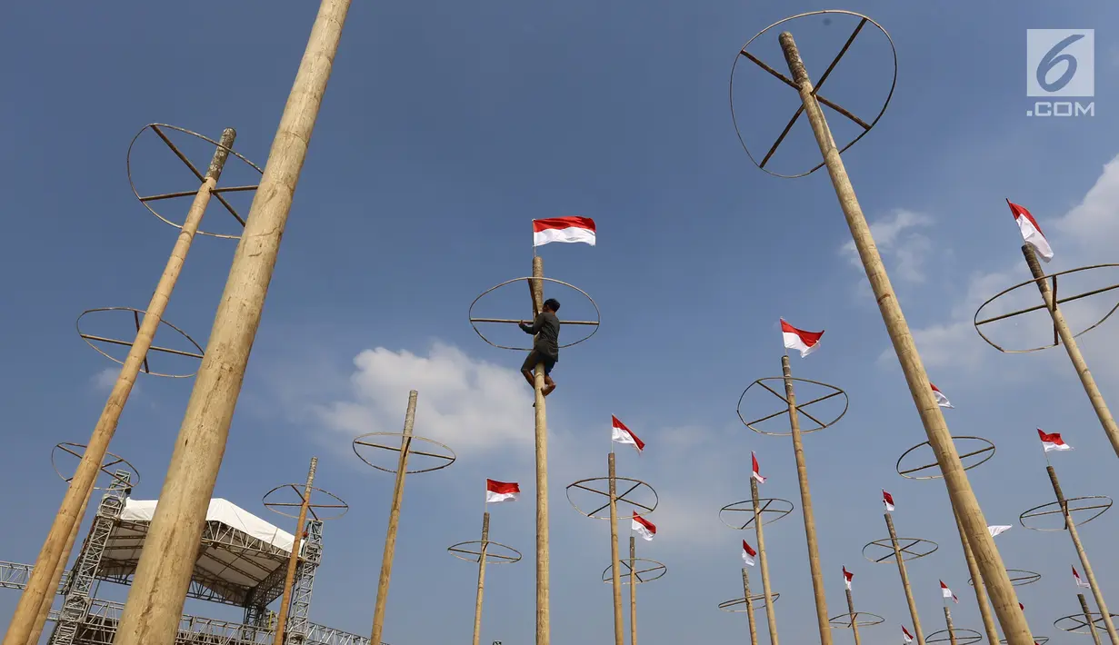 Pekerja memasang bendera Merah Putih pada pohon pinang untuk acara panjat pinang kolosal di kawasan Ancol, Jakarta, Kamis (15/8/2019). Ancol Taman Impian menggelar berbagai acara dalam menyambut HUT ke-74 RI, salah satunya adalah Panjat Pinang Kolosal. (Liputan6.com/Herman Zakharia)