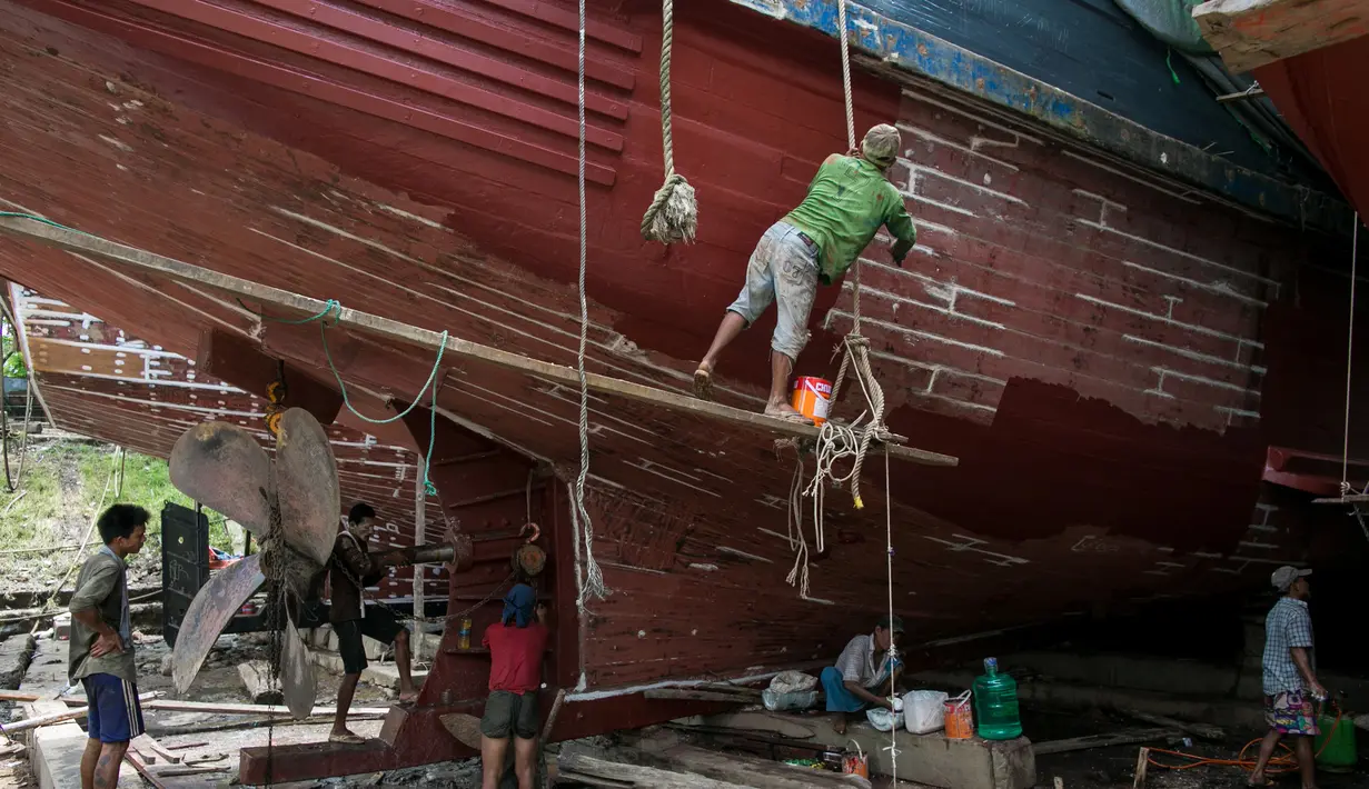 Para pekerja saat memperbaiki sebuah kapal di galangan kapal di tepi Sungai Yangon, yang terletak di pinggiran Yangon, Myanmar (30/7/2019). (AFP Phot/Sai Aung Main)