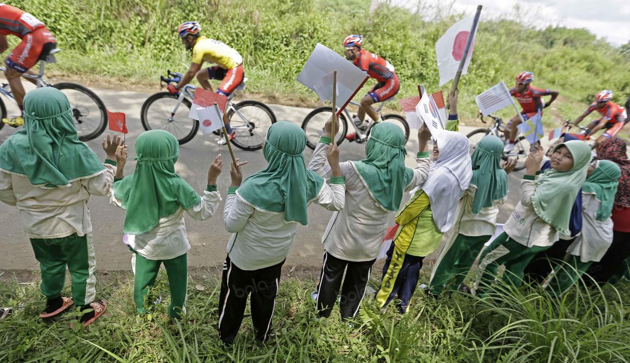 Anak-anak sekolah memberikan semangat untuk para pebalap saat Tour de Singkarak 2016 di daerah Dharmasraya, Sumatera Barat, Jumat (12/8/2016). (Bola.com/Nicklas Hanoatubun)