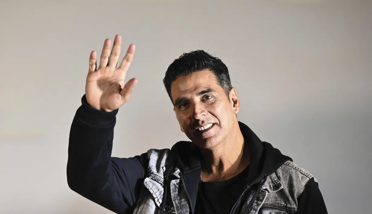 Aktor Bollywood Akshay Kumar menyapa penggemar selama acara promosi filmnya 'Raksha Bandhan' di Kolkata (8/8/2022). Akshay tampil necis dalam setelan olahraga hitam dan jaket denim. (AFP/Dibyangshu Sarkar)