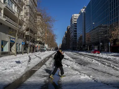 Seorang perempuan berjalan melewati salju di Madrid, Spanyol, Senin (11/1/2021). Ibu kota Spanyol itu berusaha bangkit kembali setelah menghadapi badai salju terburuk dalam 50 tahun terakhir yang melumpuhkan sebagian besar wilayah Spanyol tengah selama akhir pekan. (AP Photo/Manu Fernandez)