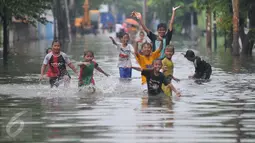 Sejumlah anak bermain saat banjir melanda kawasan Rawa Buaya, Jakarta, Minggu (28/2/2016). Banjir terjadi akibat luapan Kali Mookervart yang diguyur hujan sejak malam. (Liputan6.com/Gempur M Surya)