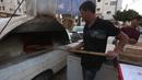Penjual roti Palestina Mohammed Abu Saud menyiapkan roti di Kota Nablus, Tepi Barat, (3/5/2020). Abu Saud, yang kehilangan pekerjaannya sebagai pekerja transportasi karena kebijakan lockdown selama pandemi COVID-19, memutuskan bekerja sebagai penjual roti keliling. (Xinhua/Ayman Nobani)