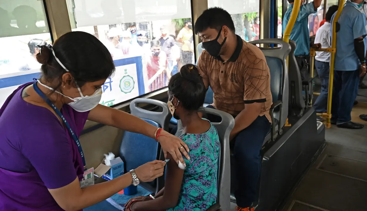 Seorang pekerja menerima suntikan vaksin Covid-19 Covishield di dalam bus penumpang yang diubah menjadi pusat vaksinasi keliling di Kolkata, Kamis (3/6/2021). India telah menderita pandemi yang menghancurkan sejak April, dan baru-baru ini mulai mereda. (Dibyangshu SARKAR/AFP)
