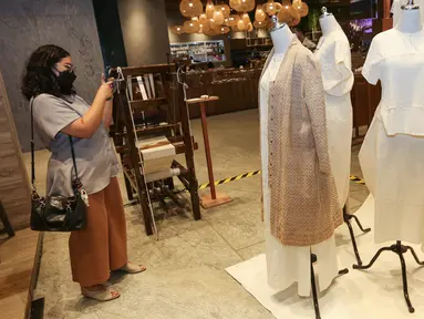 Pengunjung mengambil foto baju dalam pameran SukkhaCitta bertajuk KAPAS di ASHTA District 8, Jakarta, Jumat (22/4/2022). SukkhaCitta menceritakan  penerapan sustainable fashion dalam bisnisnya untuk melindungi lingkungan hidup sekaligus meningkatkan kesejahteraan dan pengembangan masyarakat daerah perkampungan Jawa Tengah dan Jawa Timur. (Liputan6.com/Fery Pradolo)