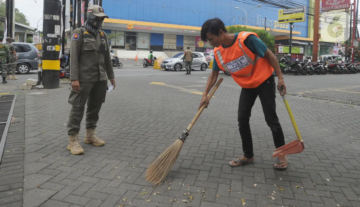 Warga pelanggar PSBB dihukum menyapu saat razia di Jalan Raya Cinere, Depok, Jawa Barat, Senin (24/8/2020). Razia ditujukan bagi warga yang tidak mengenakan masker untuk menekan penyebaran COVID-19. (merdeka.com/Arie Basuki)