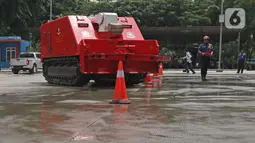 Petugas pemadam kebakaran mengoperasikan robot damkar jenis Dok-INK MVF- U3 di kantor PKP DKI Jakarta, Kamis (13/2/2020). Robot yang besarnya berkisar 3x4 meter dan digerakkan dengan remote control ini memiliki kapasitas volume air 2.500 liter dan foam 500 liter. (Liputan6.com/Herman Zakharia)