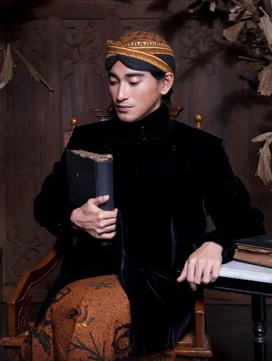 Bio One tampil gagah dibalut pakaian adat Jawa yang lengkap dengan belangkonnya, Wajah tampannya juga semakin lengkap dengan pose duduk di kursi sambil tangan kanan mendekap sebuah buku. Pandangannya juga sangat natural dengan pembawaan yang terkesan begitu wibawa. (Liputan6.com/IG/@bojvoyej)