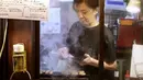 Seorang pemilik bar menyiapkan Yakitori di area jalan malam belakang pusat kota Tokyo (4/10/2019). Yakitori merupakan sate khas dari Jepang yang umumnya menggunakan daging ayam.  (AP Photo/Mark Baker)