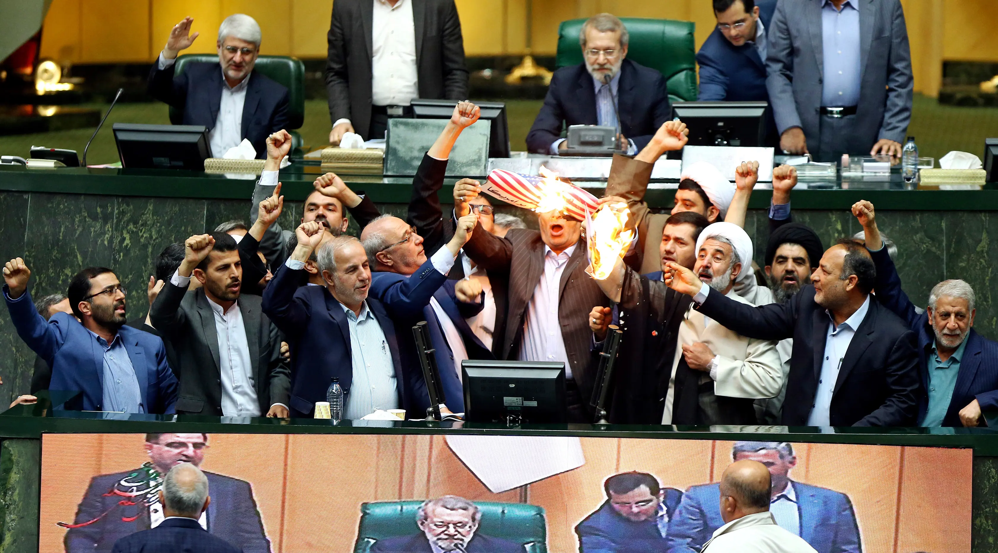 Anggota parlemen Iran membakar dua lembar kertas bergambar bendera AS, Teheran, Iran, Rabu (9/5). Aksi itu dilakukan sebagai kecaman atas kebijakan Presiden AS Donald Trump yang keluar dari kesepakatan nuklir Iran. (AP Photo)