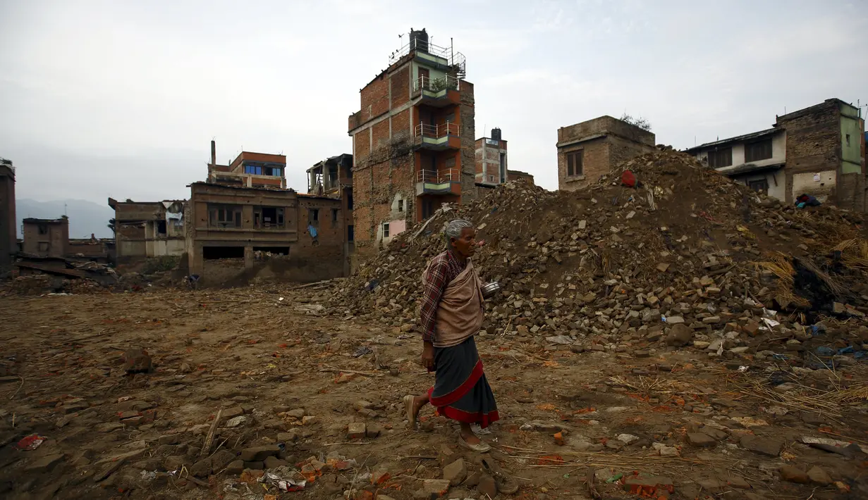 Seorang warga berjalan melewati runtuhan banguan yang rusak akibat gempa di Bhaktapur, Nepal (14/7/2015). PBB melaporkan dua bulan setelah gempa di Nepal, warga masih sulit mendapatkan makanan dan perawatan kesehatan. (REUTERS/Navesh Chitrakar)