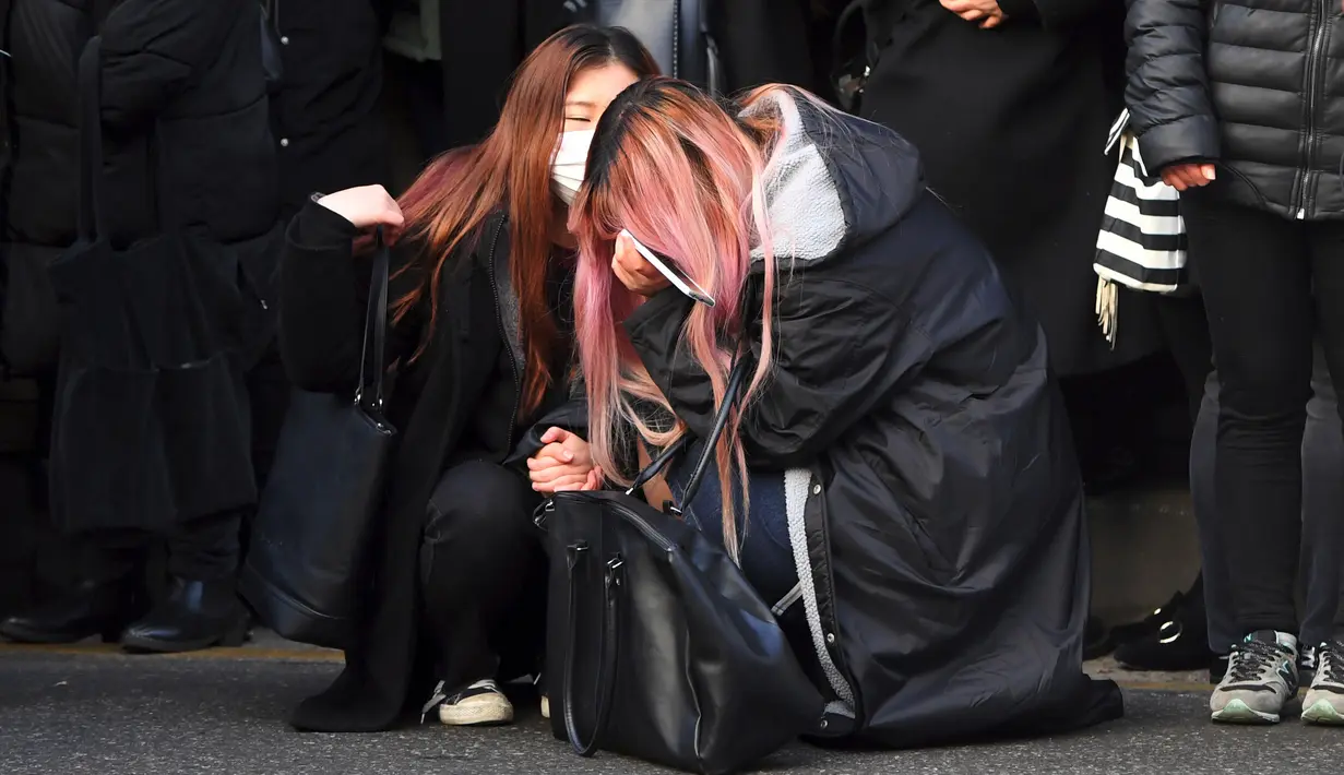 Tangis fans saat mobil yang membawa jenazah Jonghyun SHINee keluar dari rumah persemayaman di Asan Hospital, Seoul menuju tempat pemakaman, Kamis (21/12). Keluarga dan sahabat dekat mengantar Jonghyun ke tempat peristirahatan terakhir. (JUNG Yeon-Je/AFP)