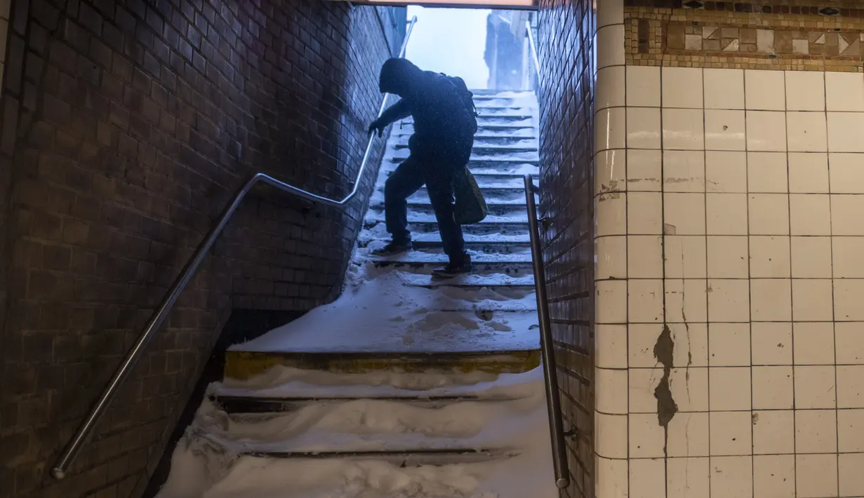 Seorang pria dengan hati-hati menuruni tangga subway yang tertutup salju selama badai salju di Bushwick, wilayah Brooklyn di New York, Sabtu (29/1/2022). Orang-orang dari New York City hingga Maine terbangun karena salju tebal dan angin kencang saat badai salju yang kuat melanda (AP/Britania Newman)