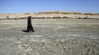 Seorang pria berjalan di tanah garam dekat Danau Razzaza, juga dikenal sebagai Danau Milh, di kegubernuran Karbala, Irak, 14 Februari 2022. Danau Razzaza Irak pernah menjadi objek wisata terkenal dengan pemandangan indahnya dan banyak ikan yang menjadi andalan penduduk setempat. (AP/Hadi Mizban)