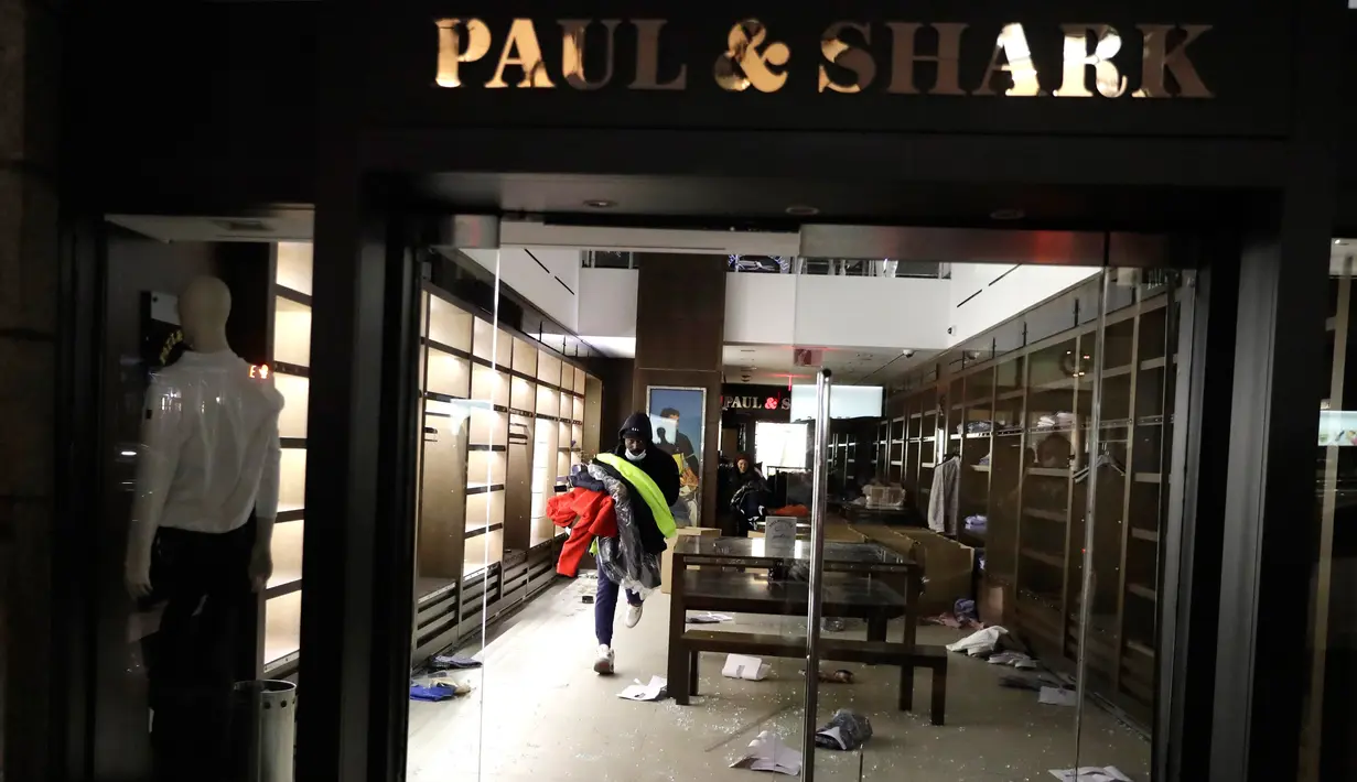 Seorang pria membawa barang yang dijarah dari sebuah toko di New York, Selasa (1/6/2020). Sejumlah toko di Amerika Serikat dijarah oleh pendemo yhang mengecam kematian warga kulit hitam George Floyd. (AP Photo/Seth Wenig)