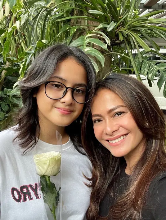 Ersa Mayori tampil bak kakak bagi anak perempuannya, Kika. Dalam foto ini, Kika yang mengenakan white t-shirt memberikan bunga tanda cinta untuk sang ibu yang terlihat mengenakan black top. Foto: Instagram.
