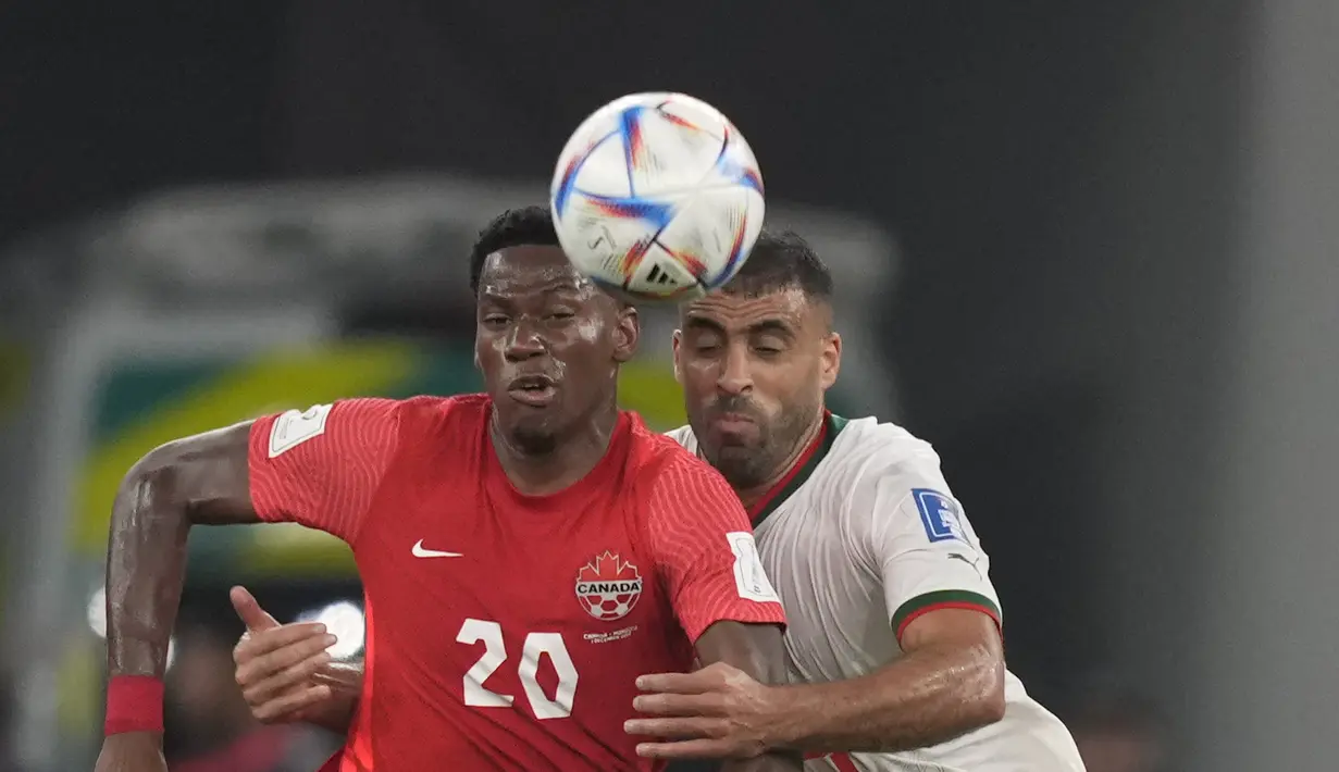<p>Penyerang Maroko, Abderrazak Hamdallah berebut bola dengan pemain Kanada, Jonathan David selama pertandingan grup F Piala Dunia 2022 di Stadion Al Thumama di Doha, Qatar, Kamis (1/12/2022). Maroko menang tipis atas Kanada dengan skor 2-1. (AP Photo/Frank Augstein)</p>