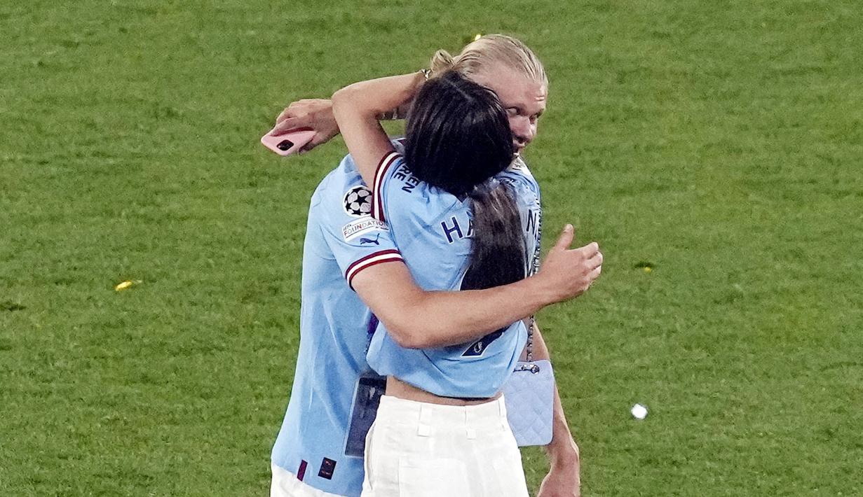 Pemain Manchester City, Erling Haaland, berpelukan dengan kekasihnya Isabel Haugseng Johansen saat perayaan gelar juara Liga Champions di Ataturk Olympic Stadium, Istanbul, Minggu (11/6/2023). Erling Haaland tampil luar biasa dan mampu meraih treble winner di musim perdananya bersama City.  (AP Photo/Thanassis Stavrakis)