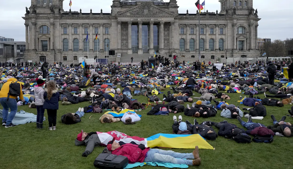 Orang-orang berbaring di tanah melambangkan mereka yang tewas dalam perang di Ukraina selama demonstrasi menentang invasi Rusia, di depan gedung Reichstag di Berlin, Jerman, 6 April 2022. Pengunjuk rasa menuntut Berlin berhenti membeli minyak dan gas Rusia. (AP Photo/Markus Schreiber)