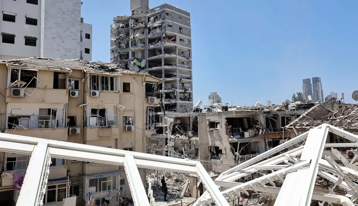 Di Bat Yam, Israel, sebuah Gedung hancur menyusul serangan Iran sepanjang Sabtu hingga Minggu 15 Juni 2025. Petugas darurat terus menyisir lokasi kejadian dengan bantuan anjing pelacak. (GIL COHEN-MAGEN/AFP)