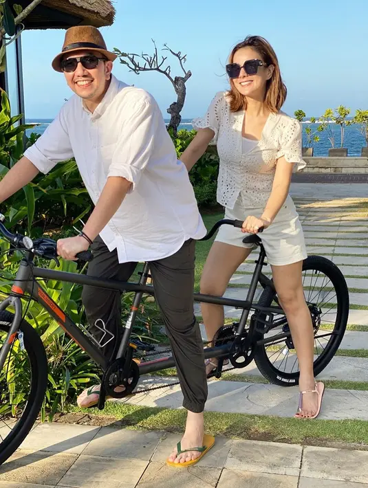 Dibarengi semilir angin pantai, presenter 36 tahun ini memamerkan keromantisan mengendarai sepeda bareng suami. Pasangan yang telah memiliki dua orang anak ini kompak dengan busana putih dan kacamata hitamnya. Tak lupa, keduanya juga tersenyum menunjukkan gigi ke arah kamera. (Liputan6.com/IG/@astridtiar127)