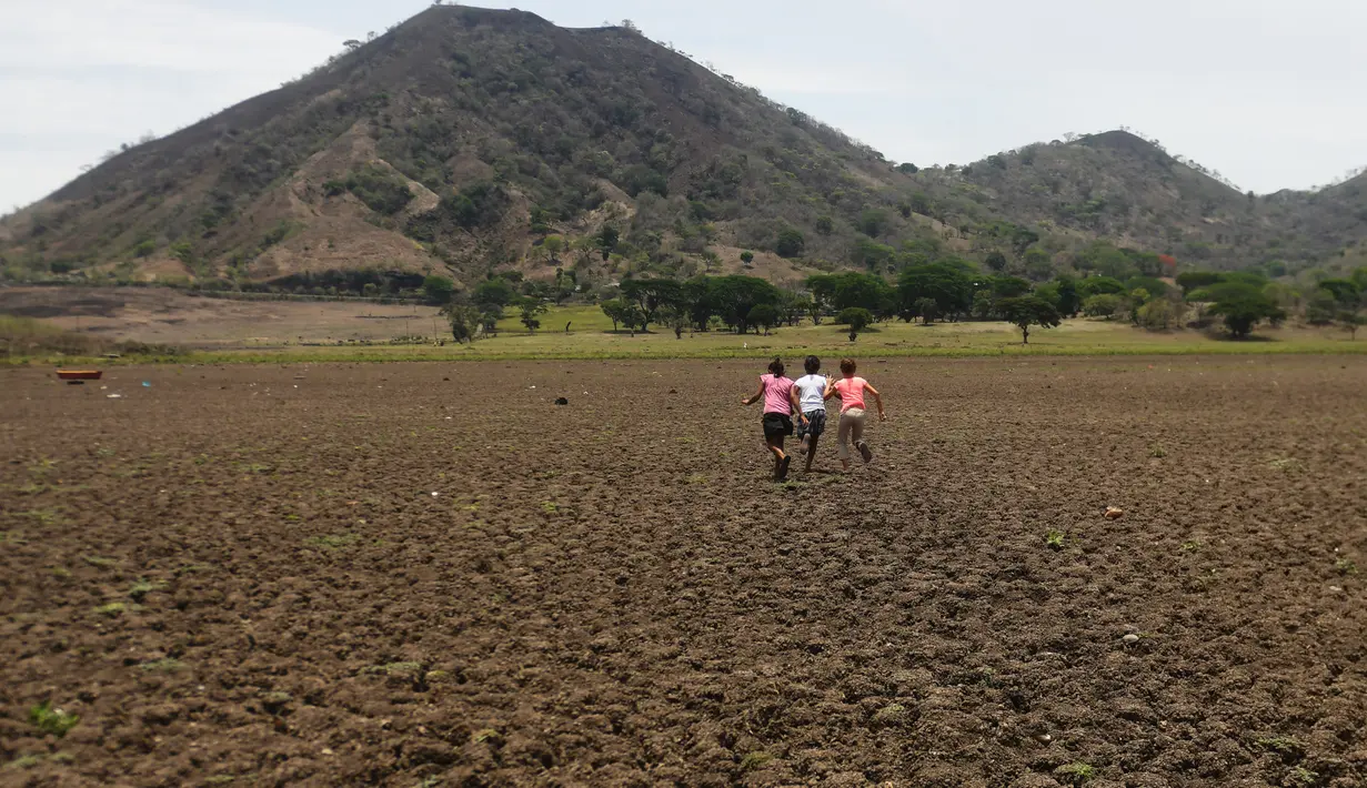 Sejumlah anak berlari di daratan bekas Danau Atescatempa yang telah mengering, Guatemala, Jumat (5/5). Dari bulan Juli, El Nino, sistem cuaca tidak teratur yang menaikkan suhu Samudera Pasifik dan menyebabkan kekeringan. (AFP PHOTO / Marvin RECINOS)