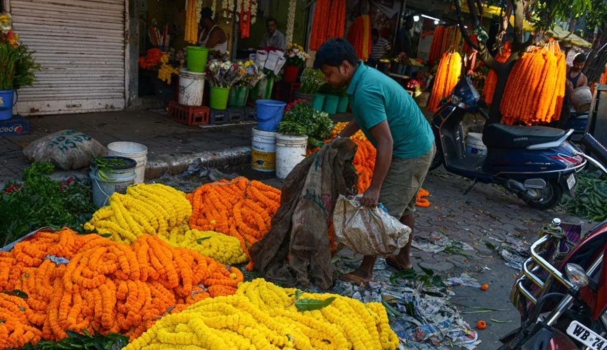 Seorang pedagang menjajakan bunga untuk dijual selama Festival Durga Puja di pinggir jalan Siliguri, India, Selasa (12/10/2021). Durga Puja juga disebut Durgotsab adalah festival tahunan di Asia Selatan untuk memuja dewi Durga dari agama Hindu. (DIPTENDU DUTTA/AFP)