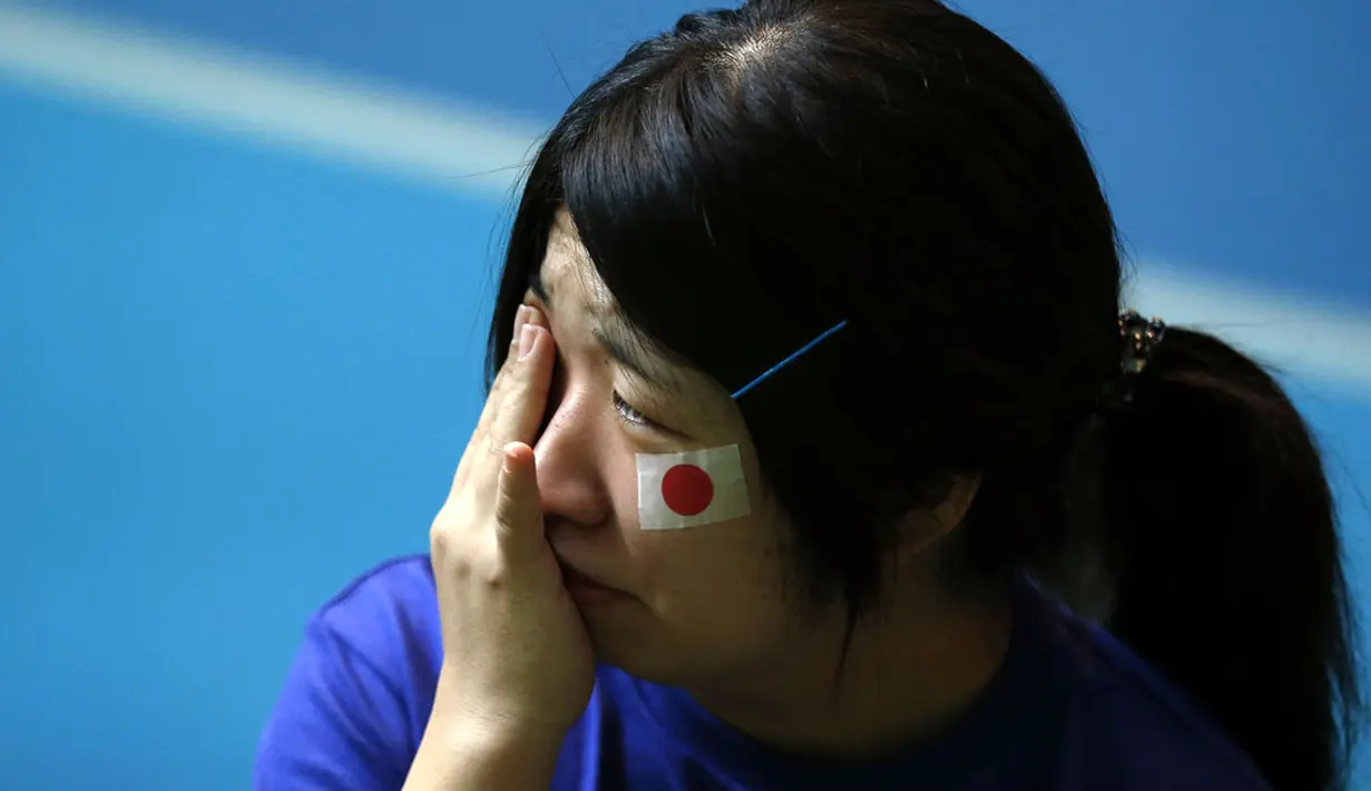 Salah satu warga Jepang di Tokyo menangis usai menyaksikan Keisuke Honda dkk dikalahkan Kolombia 1-4 di laga penutup penyisihan Piala dunia 2014 Grup C, (25/6/2014). (REUTERS/Issei Kato)
