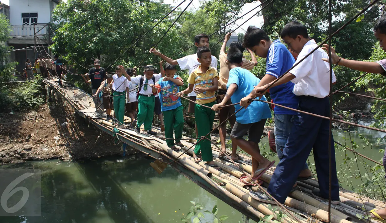 Sejumlah pelajar menyeberangi Kali Angke melewati jembatan rapuh di Kampung Cantiga, Petir, Cipondoh, Tangerang, Rabu (2/9/2015). Jembatan berusia lima tahun tersebut menghubungkan Cipondoh dan Kembangan, Jakarta. (Liputan6.com/Gempur M Surya)