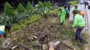 Sejumlah petugas membersihkan batang pohon yang tumbang di jalan Jenderal Sudirman, Jakarta, Senin (1/2). Pohon tumbang yang terjadi saat hujan deras mengakibatkan kemacetan panjang dikawasan tersebut. (Liputan6.com/Helmi Afandi)