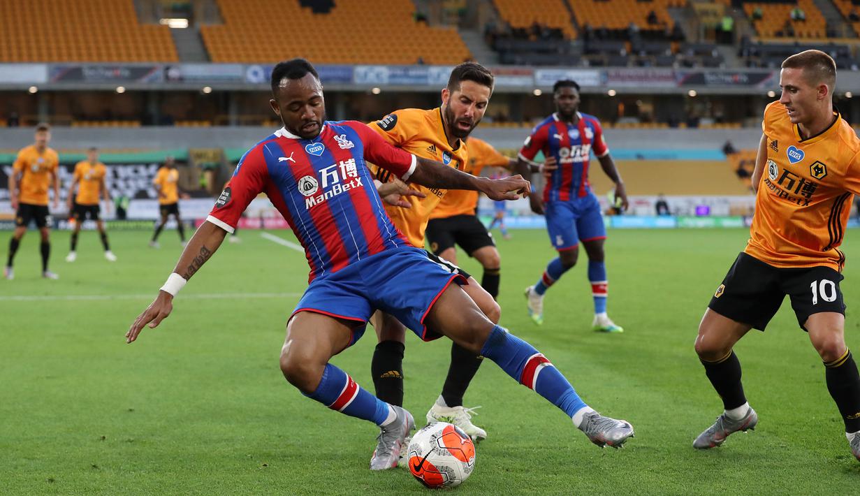 Striker Crystal Palace, Jordan Ayew, berebut bola dengan gelandang Wolverhampton Wanderers, Joao Moutinho, pada laga lanjutan Premier League di Molineux Stadium, Selasa (21/7/2020) dini hari WIB. Wolves menang 2-0 atas Crystal Palace. (AFP/Martin Rickett/pool)
