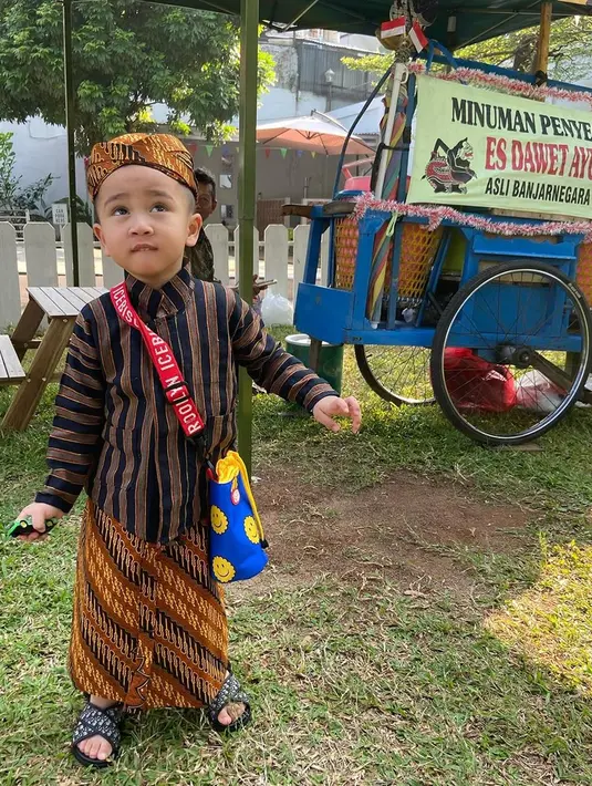 Rayyanza memadukan baju luriknya dengan kain jarik bermotif. Netizen pun memuji penampilannya yang seperti mas-mas Jawa. Meski berpakaian tradisional, rupanya sandal bocah yang segera berusia 3 tahun itu bikin salah fokus karena berasal dari merek ternama dunia, Dior. (Liputan6.com/IG/@raffinagita1717)